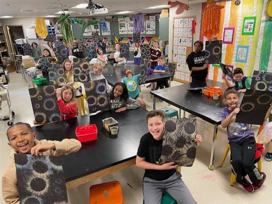 Students holding up solar eclipse artwork 